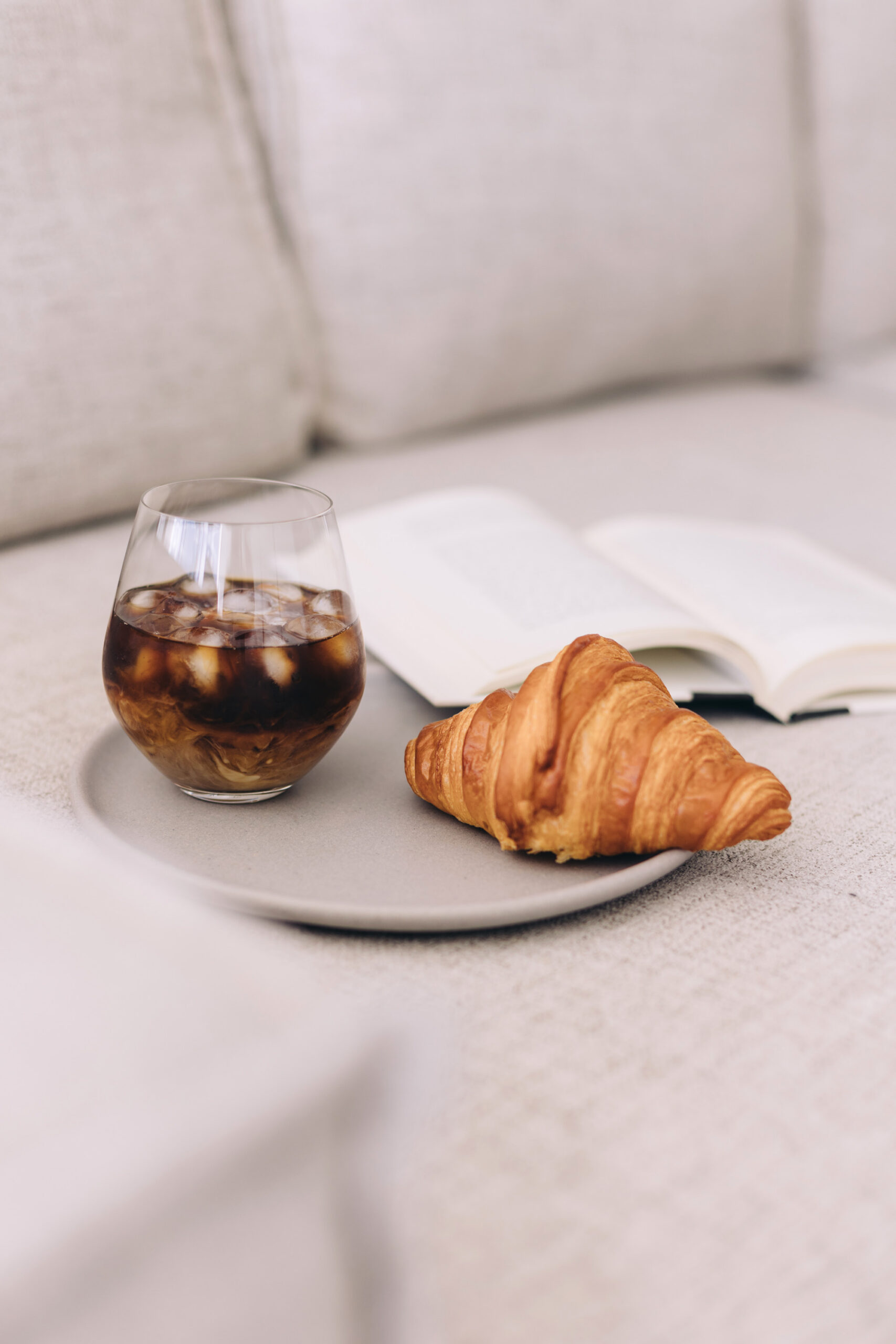 iced coffee croissant on a plate and an open book